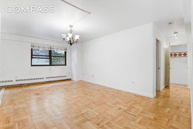 empty room featuring a baseboard heating unit, an inviting chandelier, and light parquet flooring