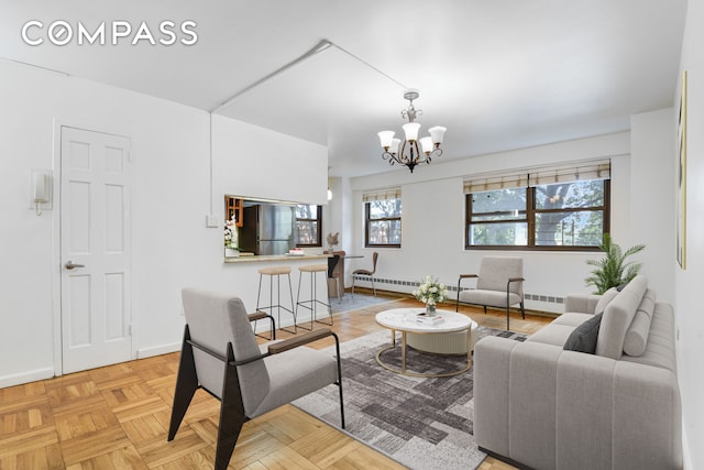 living room with a baseboard radiator, light parquet floors, and an inviting chandelier