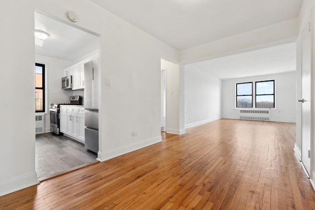 unfurnished living room with radiator heating unit and hardwood / wood-style floors