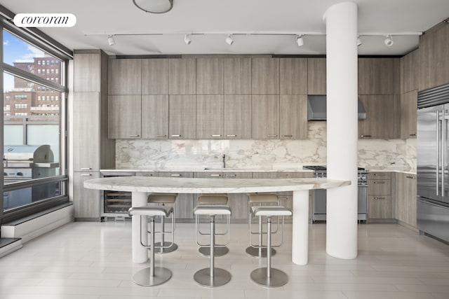 kitchen with light hardwood / wood-style floors, high end appliances, beverage cooler, a kitchen island, and a kitchen breakfast bar