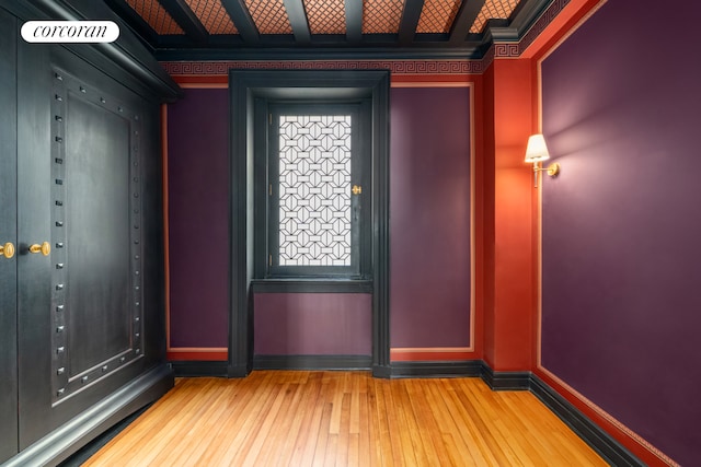 empty room featuring wood-type flooring and crown molding