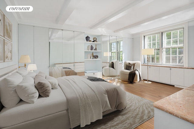 bedroom with beamed ceiling and light hardwood / wood-style floors