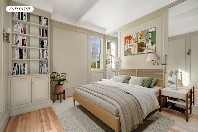 bedroom with beamed ceiling and light wood-type flooring