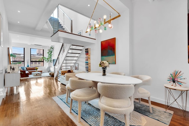 dining area with hardwood / wood-style flooring, beam ceiling, and a chandelier