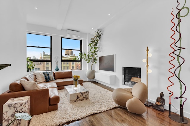 living room featuring beam ceiling, a wall mounted air conditioner, and hardwood / wood-style flooring