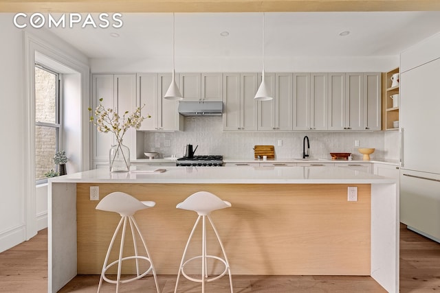 kitchen with pendant lighting, a breakfast bar area, light hardwood / wood-style flooring, and an island with sink