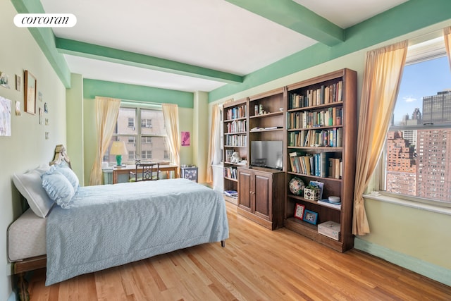 bedroom featuring light wood-type flooring and beam ceiling