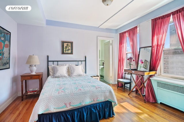 bedroom with radiator heating unit and hardwood / wood-style flooring