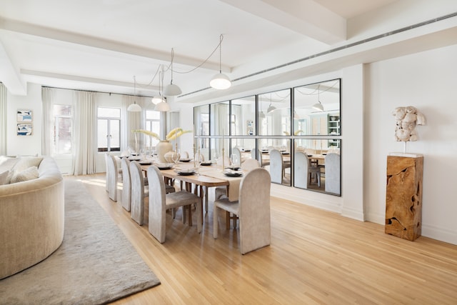 dining space with beamed ceiling and light hardwood / wood-style floors