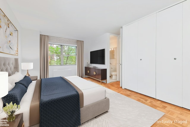 bedroom featuring connected bathroom and light parquet floors