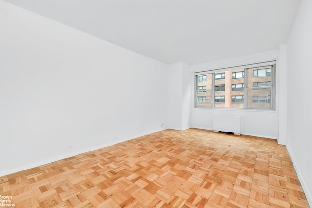 unfurnished room featuring radiator heating unit and light parquet flooring