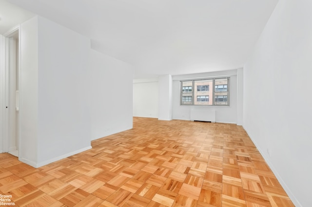 unfurnished living room featuring radiator and light parquet floors