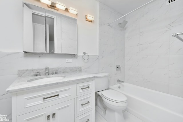 full bathroom with tile walls, tiled shower / bath, vanity, and toilet