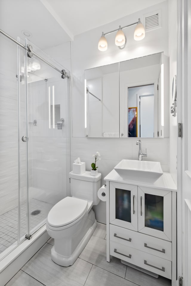 bathroom featuring toilet, tile patterned flooring, vanity, and a shower with door