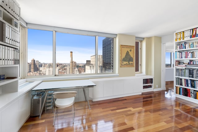 office space featuring wood-type flooring, heating unit, and a wealth of natural light