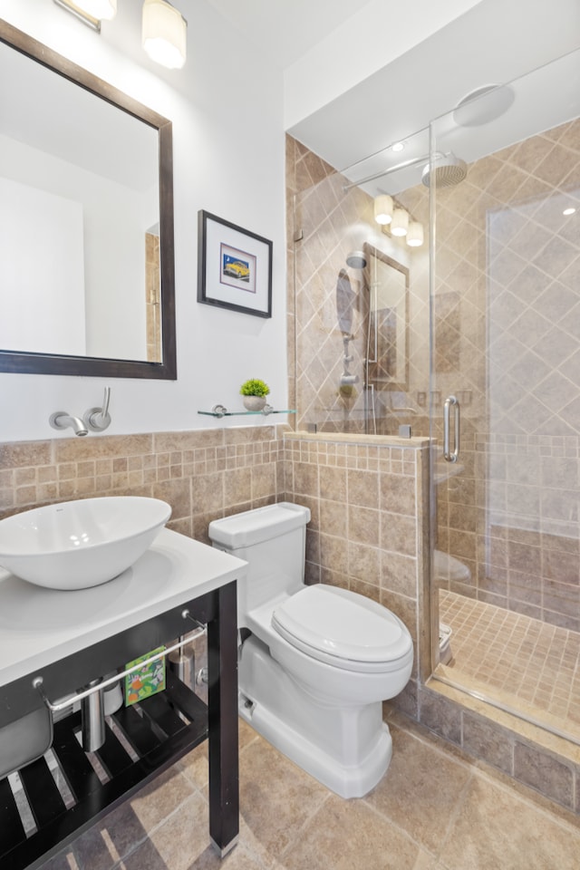 bathroom featuring tile patterned floors, toilet, vanity, tile walls, and an enclosed shower