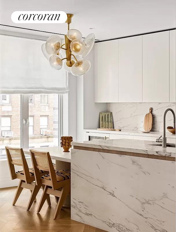 interior space featuring white cabinets, sink, decorative light fixtures, light stone countertops, and decorative backsplash