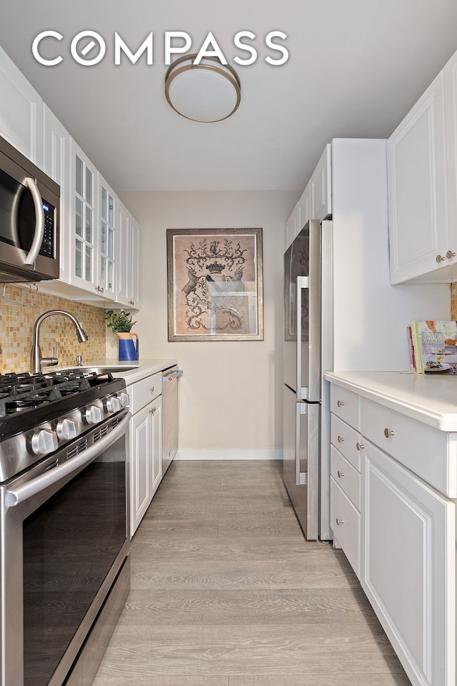 kitchen featuring white cabinetry, light hardwood / wood-style floors, appliances with stainless steel finishes, and tasteful backsplash