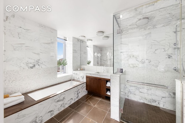 bathroom featuring tile patterned flooring, separate shower and tub, vanity, and tile walls