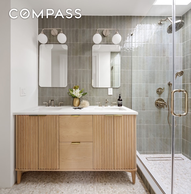 bathroom with vanity, a shower with door, and tile walls