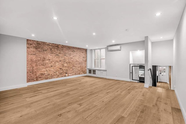 unfurnished living room with brick wall, a wall mounted air conditioner, and light wood-type flooring