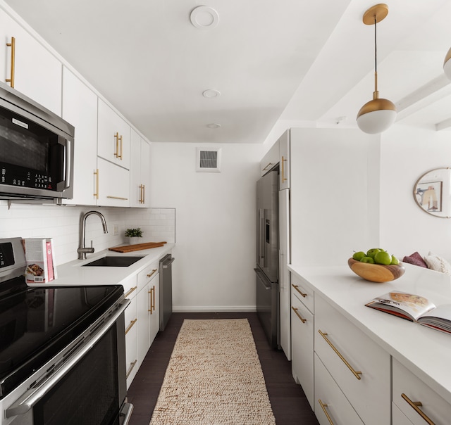 kitchen featuring appliances with stainless steel finishes, tasteful backsplash, white cabinets, dark hardwood / wood-style flooring, and sink