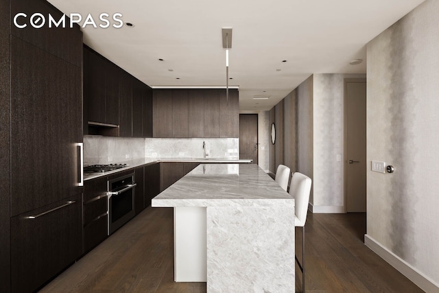 kitchen with appliances with stainless steel finishes, a center island, dark wood-type flooring, and a breakfast bar area