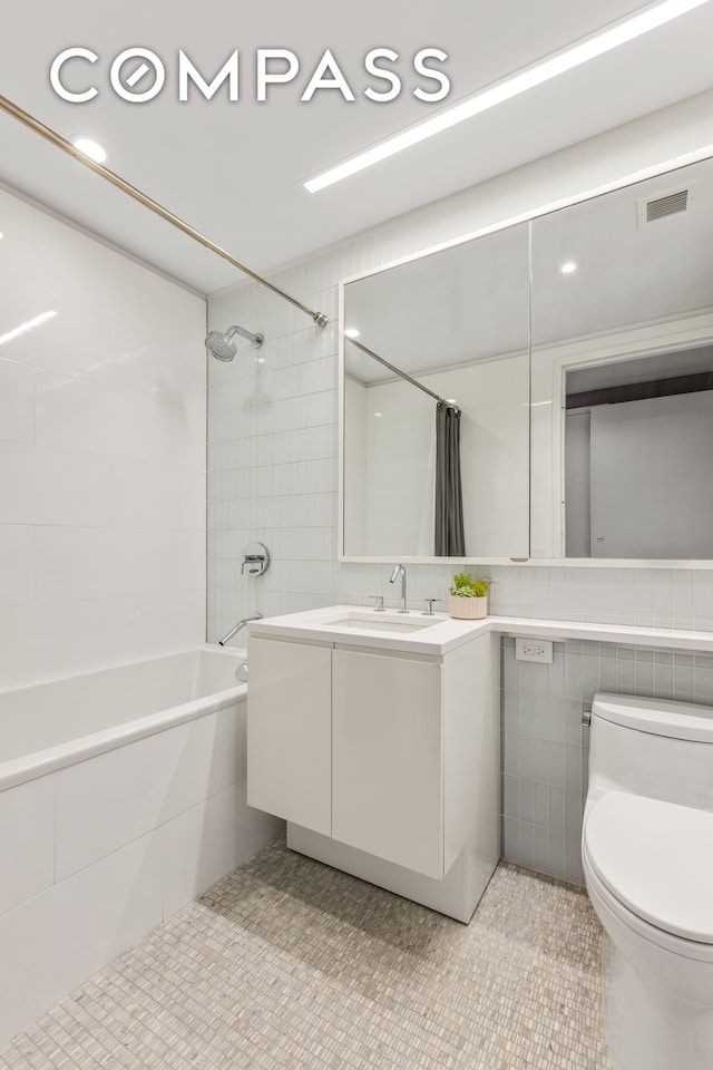 full bathroom featuring tile walls, vanity, tile patterned flooring, shower / tub combo with curtain, and toilet