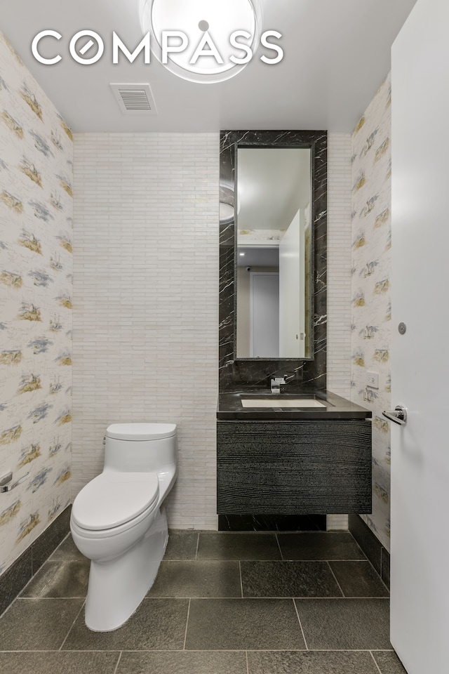 bathroom with tile walls, vanity, and toilet