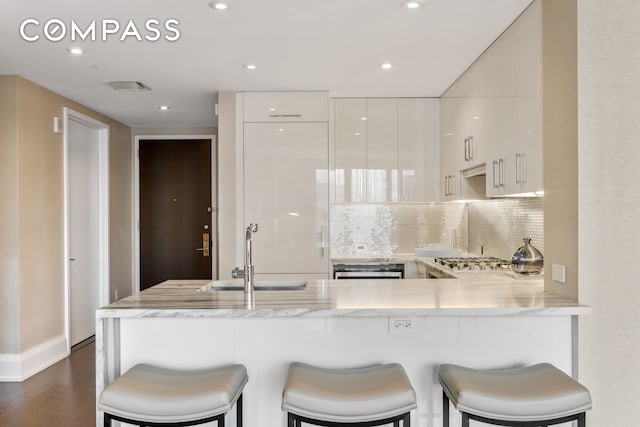 kitchen featuring a kitchen breakfast bar, kitchen peninsula, dark hardwood / wood-style floors, and sink