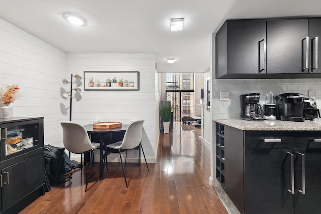 kitchen with decorative backsplash, light stone counters, and dark hardwood / wood-style floors