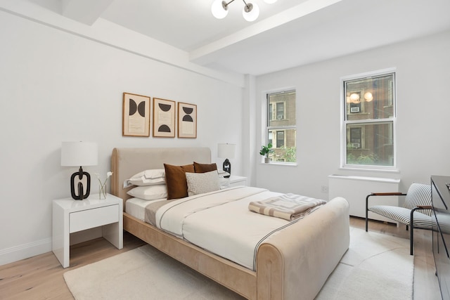 bedroom with beamed ceiling and light hardwood / wood-style floors