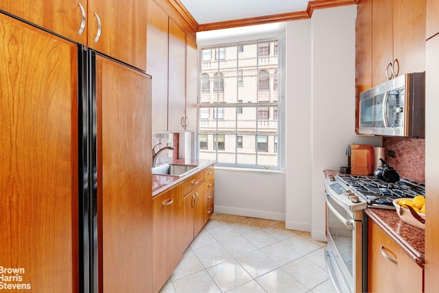 kitchen featuring white gas stove, crown molding, sink, light tile patterned floors, and built in fridge