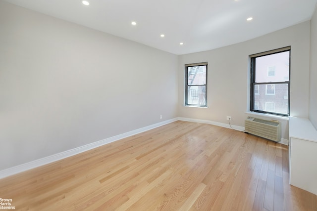 unfurnished room with light hardwood / wood-style flooring and a wall unit AC