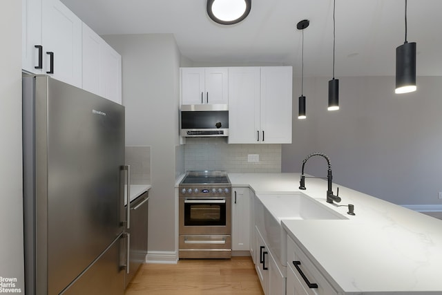 kitchen with white cabinets, appliances with stainless steel finishes, backsplash, and pendant lighting