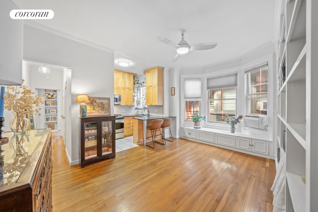 kitchen with a breakfast bar, backsplash, light brown cabinetry, light hardwood / wood-style floors, and stainless steel appliances