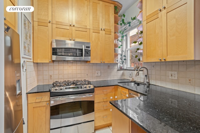 kitchen with tasteful backsplash, dark stone countertops, sink, and appliances with stainless steel finishes