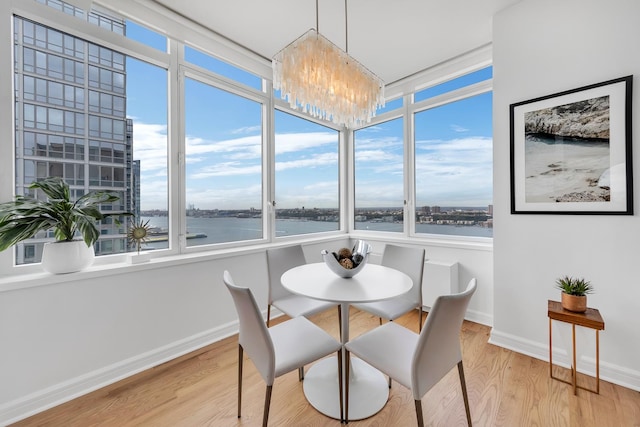 dining space with a notable chandelier, a water view, and hardwood / wood-style flooring