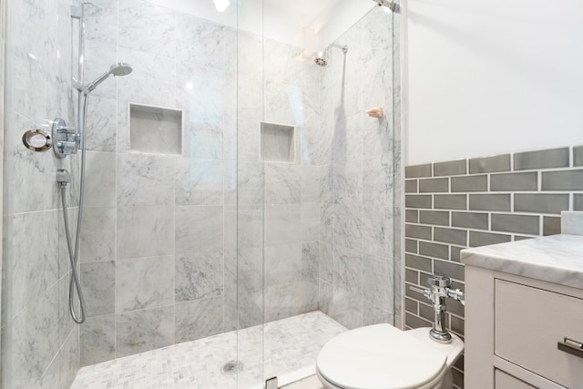 bathroom with vanity, tile walls, a shower with shower door, and toilet