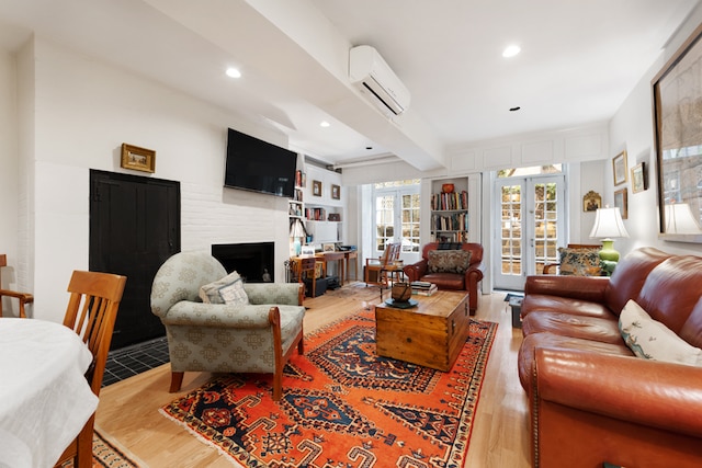 living room with beamed ceiling, hardwood / wood-style flooring, a fireplace, and an AC wall unit