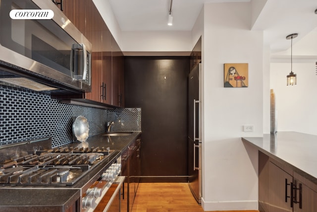 kitchen with dark brown cabinets, light wood-type flooring, appliances with stainless steel finishes, and tasteful backsplash