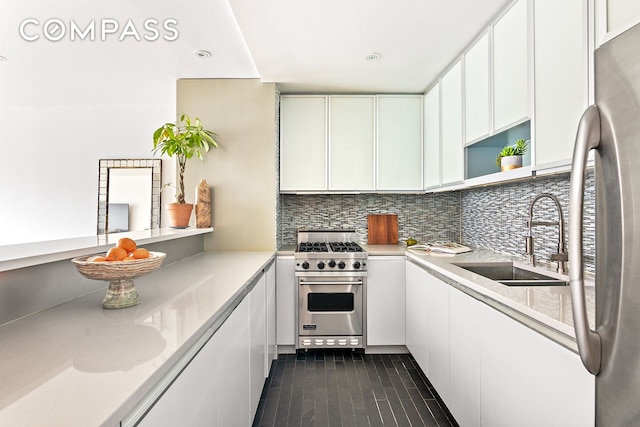 kitchen featuring stainless steel appliances, white cabinetry, tasteful backsplash, and sink