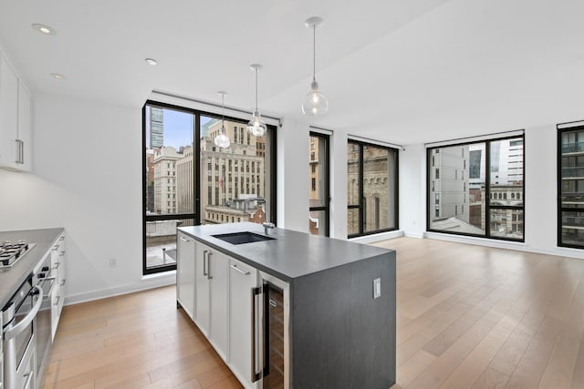 kitchen featuring white cabinets, pendant lighting, light hardwood / wood-style floors, and beverage cooler