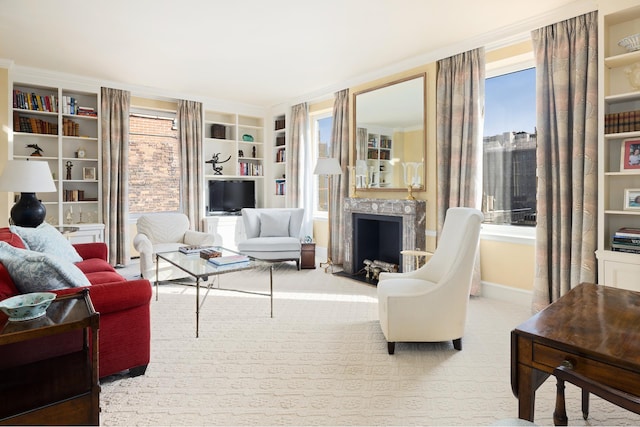 carpeted living room featuring built in features, a fireplace, and crown molding