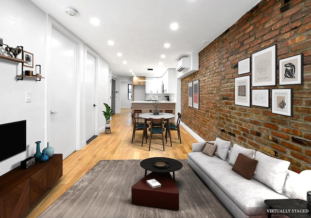 living room with light hardwood / wood-style floors, a wall mounted AC, and brick wall