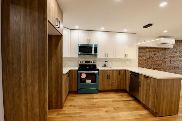 kitchen featuring white cabinets, backsplash, appliances with stainless steel finishes, light wood-type flooring, and decorative light fixtures