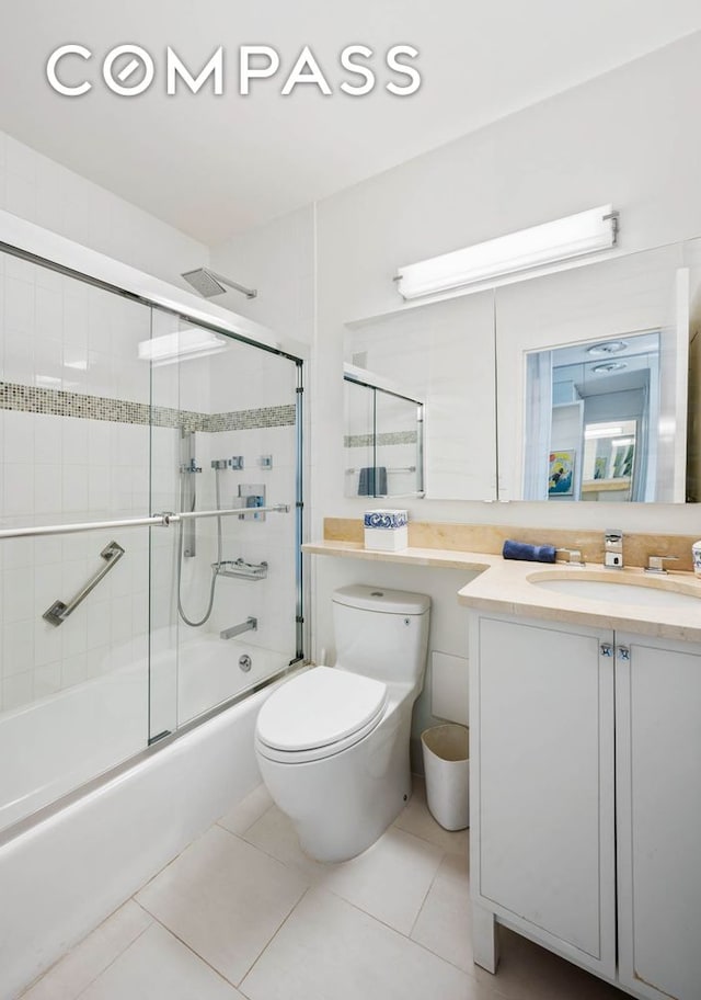 full bathroom with shower / bath combination with glass door, tile patterned flooring, vanity, and toilet