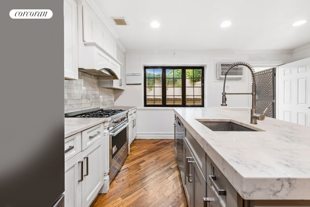 kitchen with wood-type flooring, sink, light stone countertops, appliances with stainless steel finishes, and white cabinetry