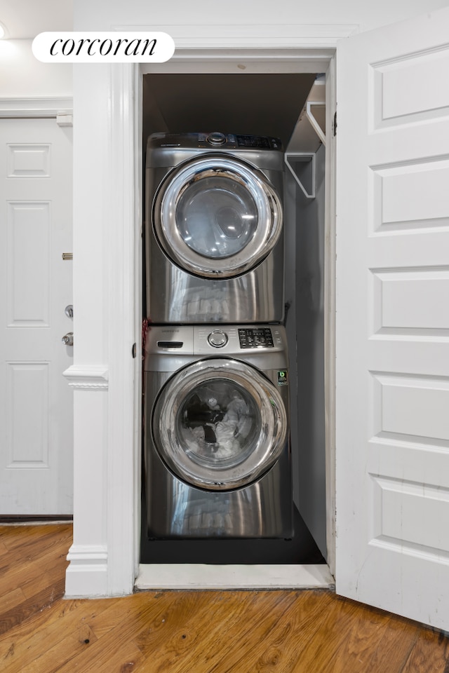 washroom with stacked washer and dryer and hardwood / wood-style flooring