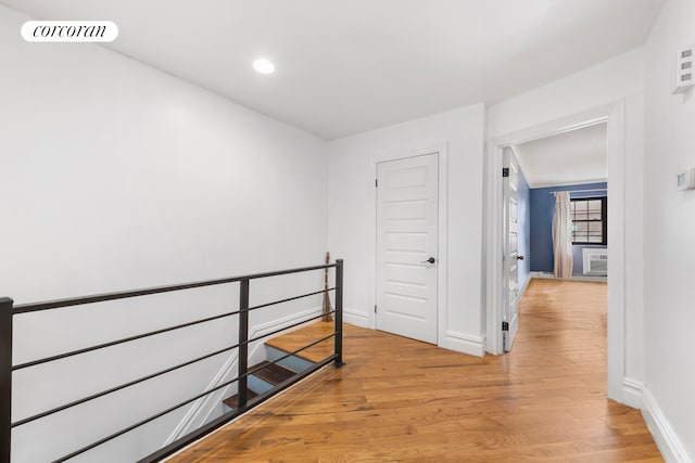 hallway featuring a wall mounted air conditioner and light hardwood / wood-style floors